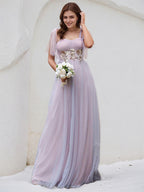 Vestido de madrinha rosa em tule, corte A, alças finas, sem mangas, comprimento até o chão, com aplicação