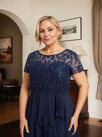 Vestido de mãe da noiva em chiffon assimétrico com decote redondo, ilusão, renda, laço, babados e lantejoulas em corte evasê