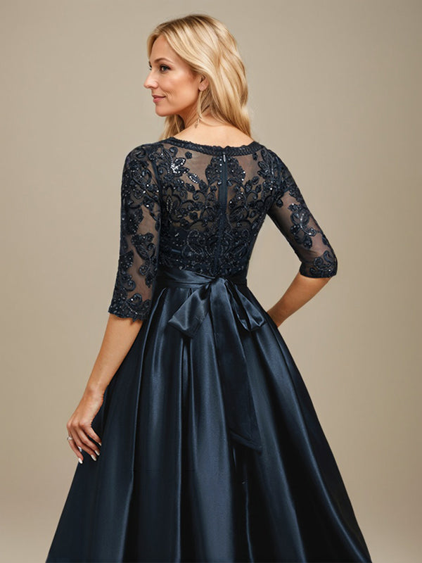 Vestido de mãe da noiva em cetim stretch com renda, comprimento até o chão, corte evasê, decote redondo com ilusão e laço com paetês