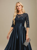 Vestido de mãe da noiva em cetim stretch com renda, comprimento até o chão, corte evasê, decote redondo com ilusão e laço com paetês