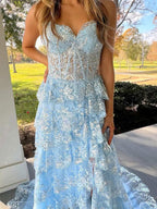 Vestido de fiesta azul línea A sin tirantes con escote en V, apliques y volantes con abertura