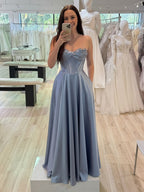 Abito da sera in raso blu polvere con corsetto senza spalline e spacco